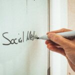 Crop anonymous male teacher writing on whiteboard with marker during social media training courses
